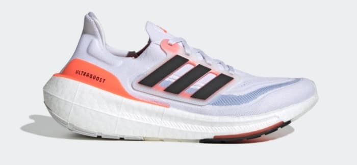 Side view of a white and orange adidas shoe.